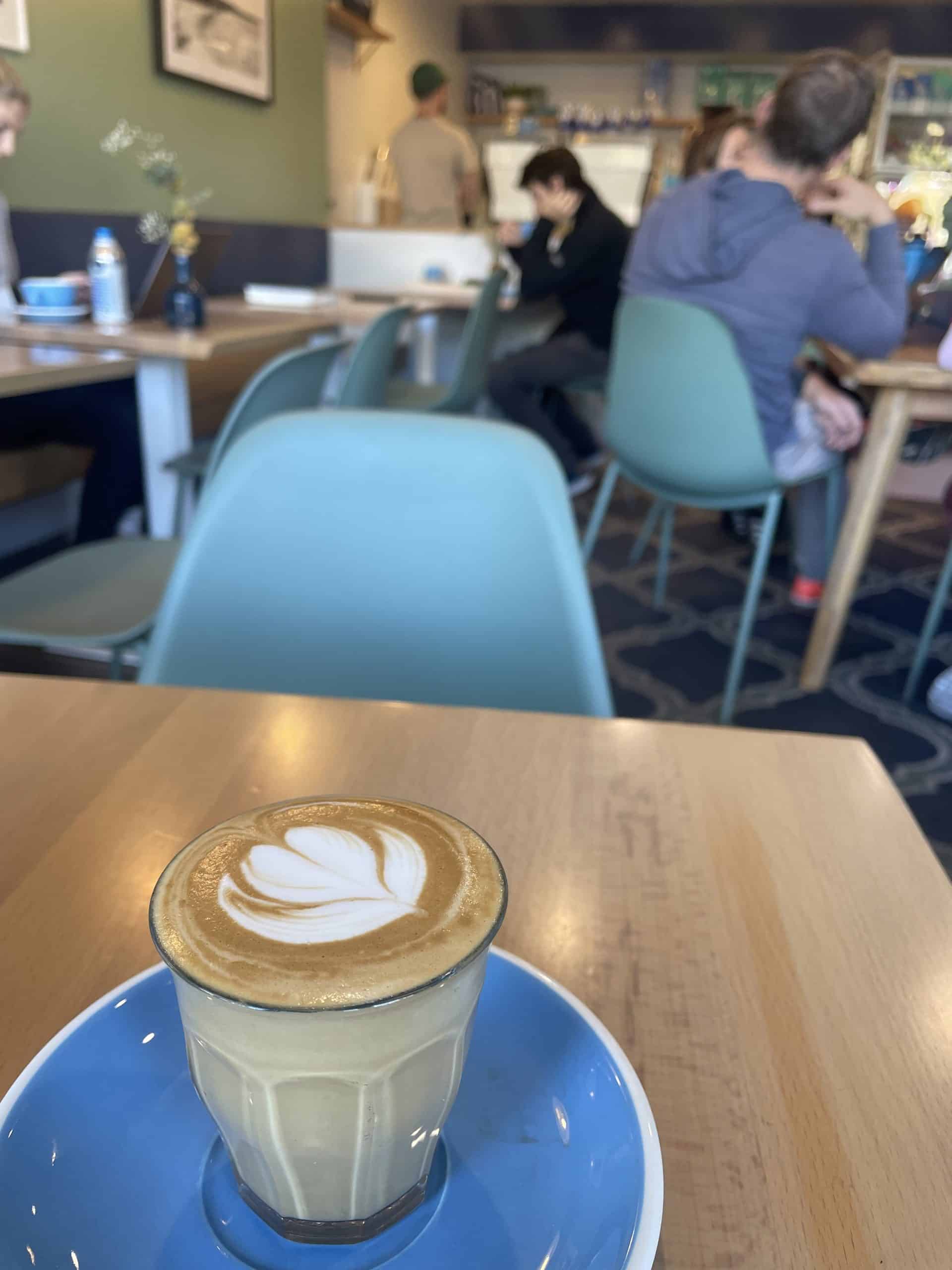 piccolo coffee in a mug on a blue plate on a wooden table at a coffee shop