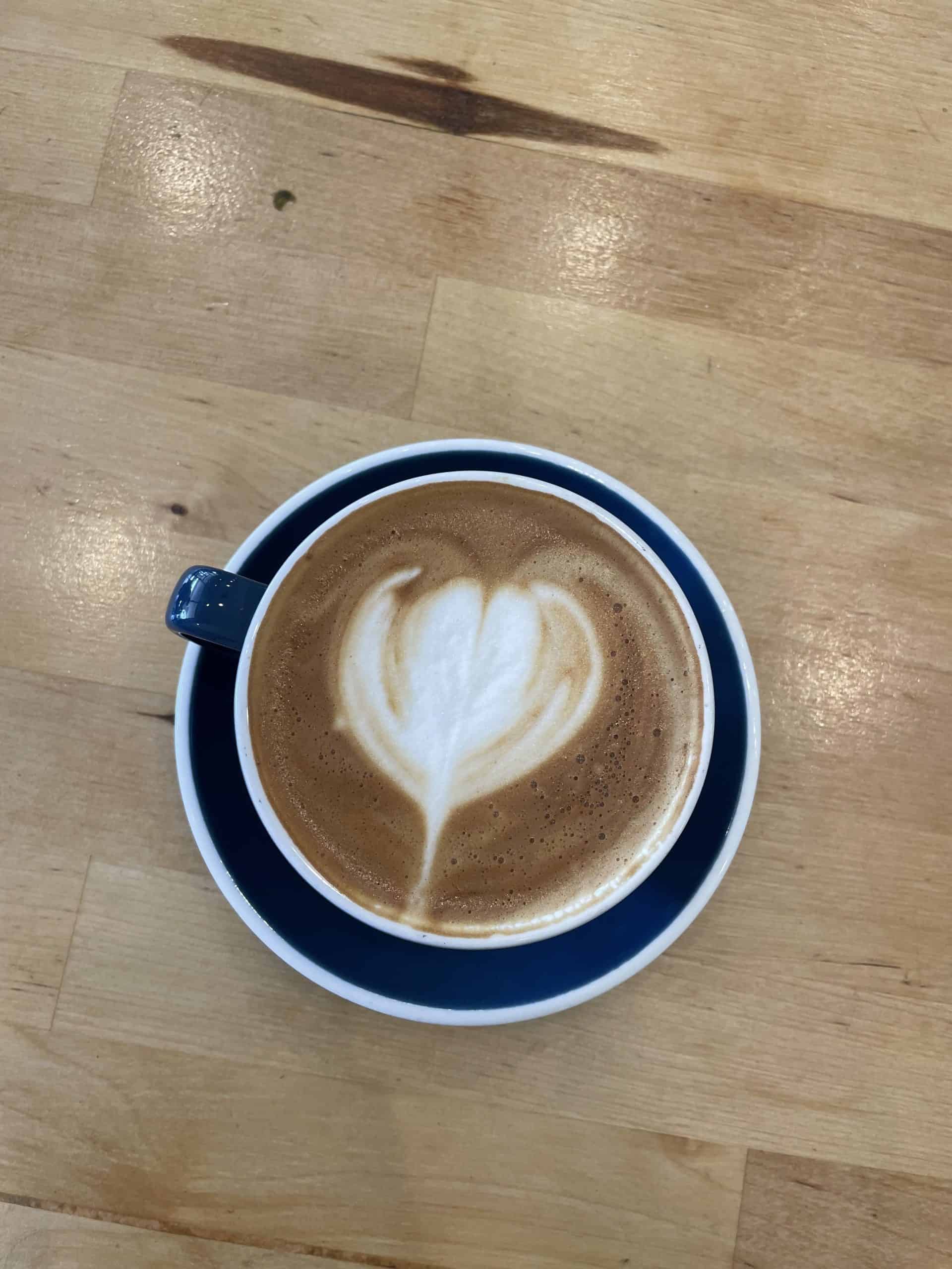 cappuccino in a navy blue mug on a wooden table in San Clemente