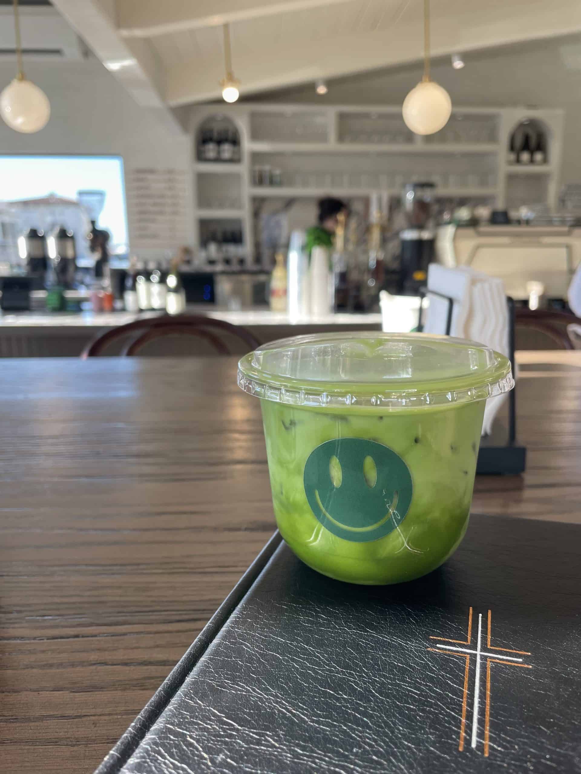 iced matcha latte in a cup with a green smiley face on it at Happy Coffee Club in San Clemente