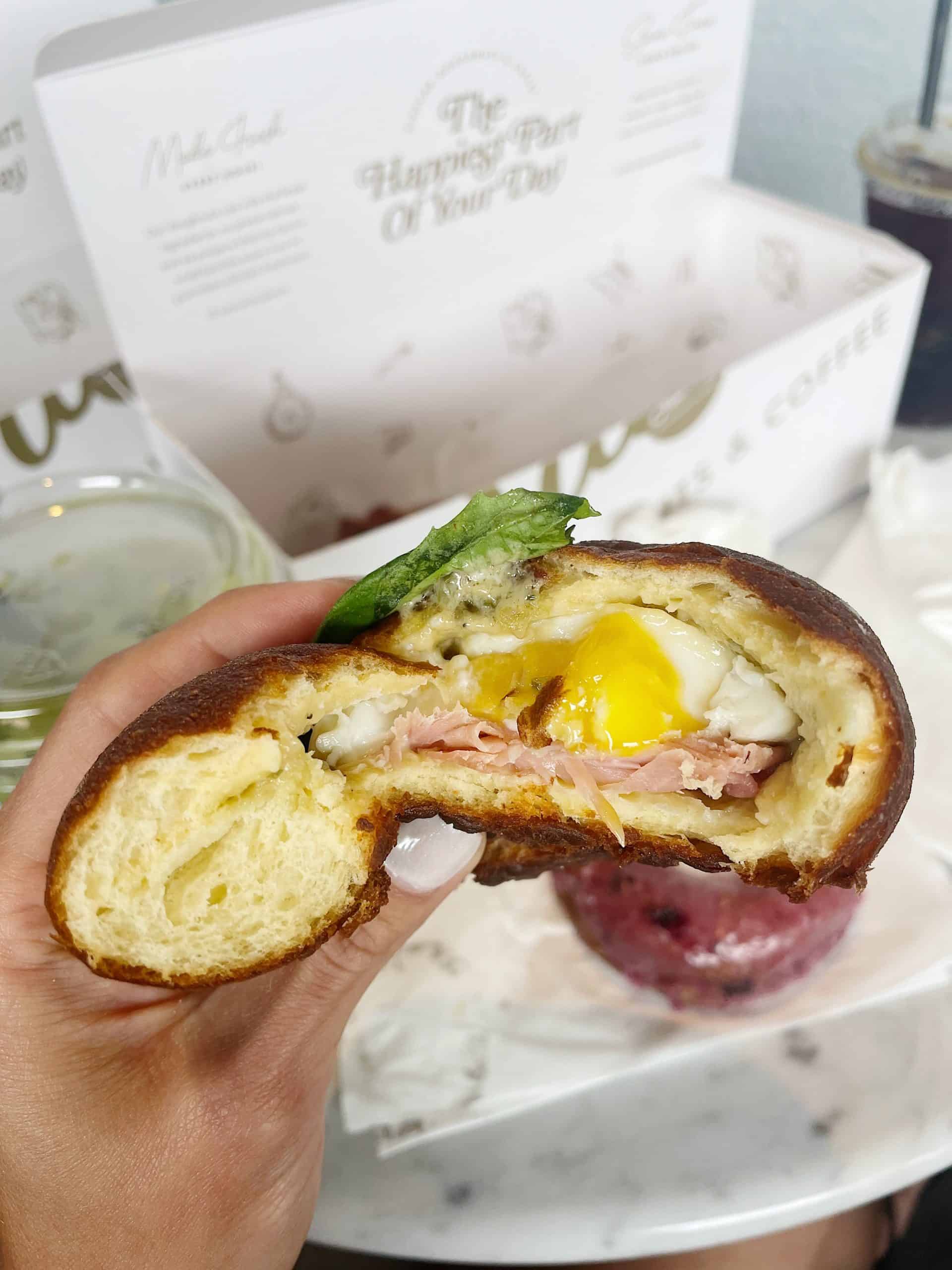 a fluffy breaded donut stuffed with egg, prosciutto and basil on top