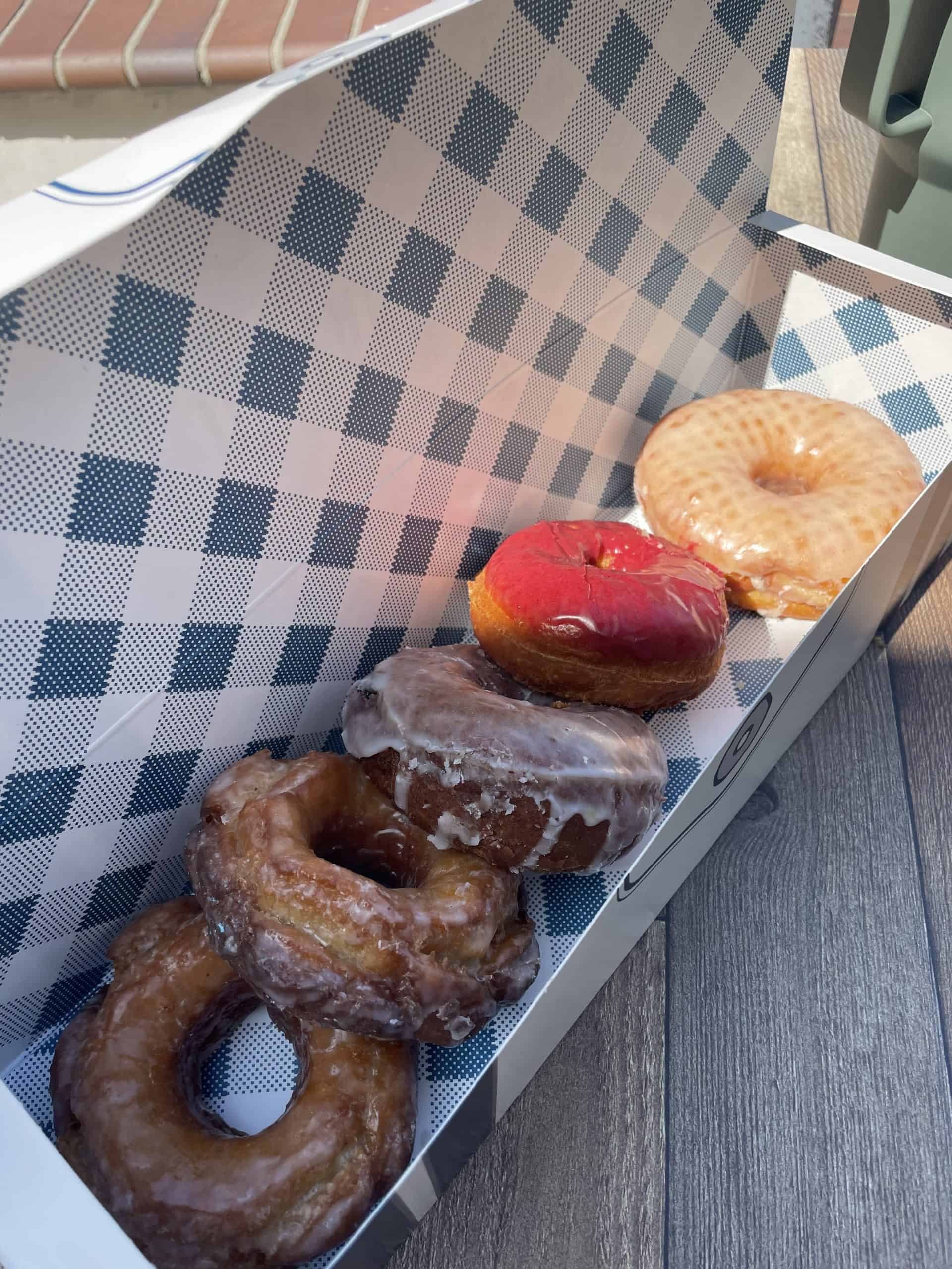 a blue and white checkered box filled with 5 donuts