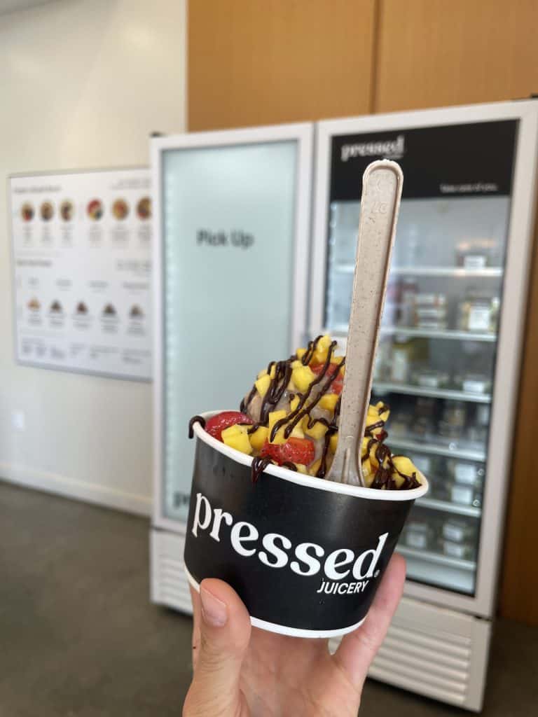 frozen yogurt with mango, strawberries and chocolate sauce in a black cup that says 'prodded juicery'