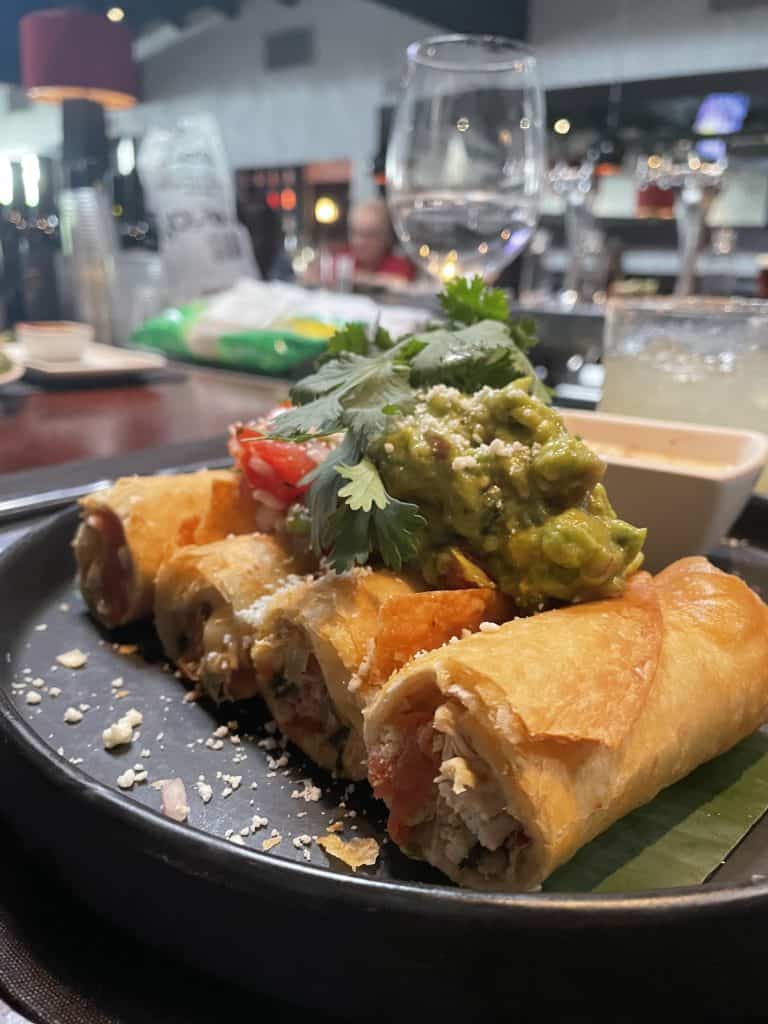 taquitos with guacamole and cilantro on top