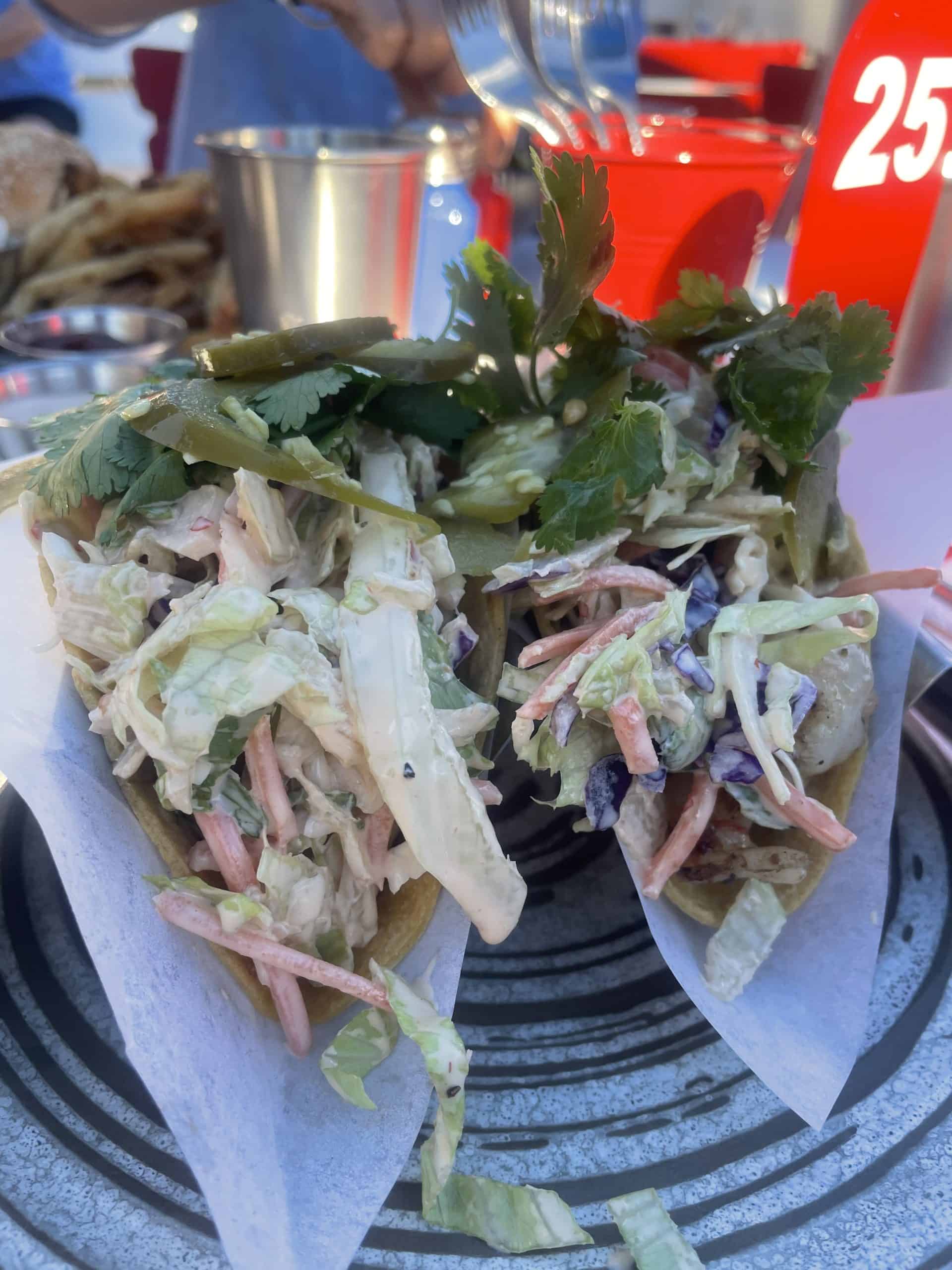 fish tacos overfilled with coleslaw and jalapeño and cilantro on top
