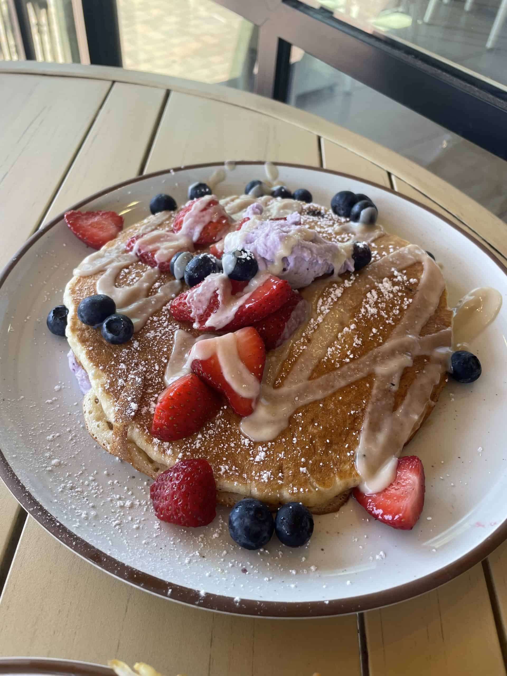 Ube pancakes with strawberries, blueberries and syrup on top
