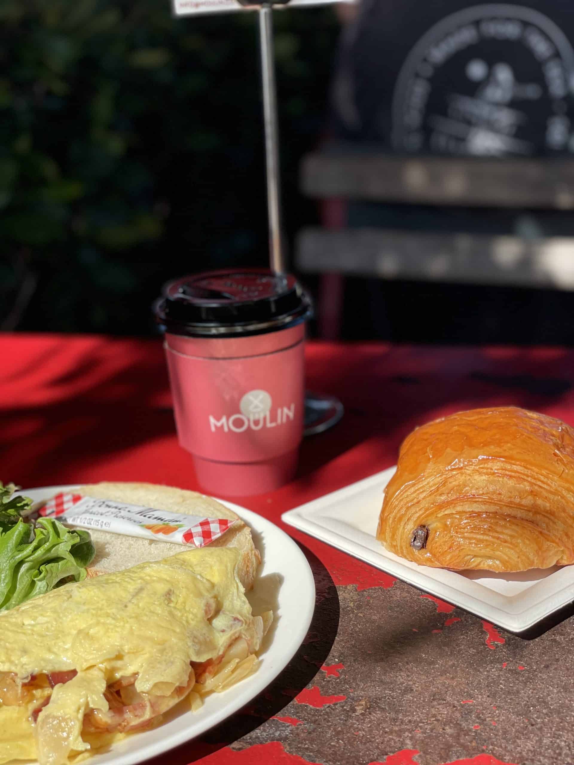 omelette with a chocolate croissant and a red and black coffee cup at Moulin in San Clemente
