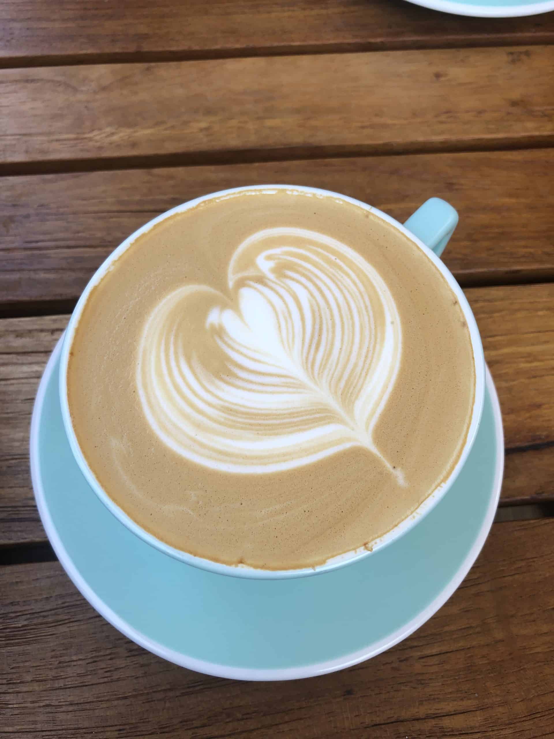 a latte in a sea foam blue cup with a heart latte art at a breakfast spot in Orange County