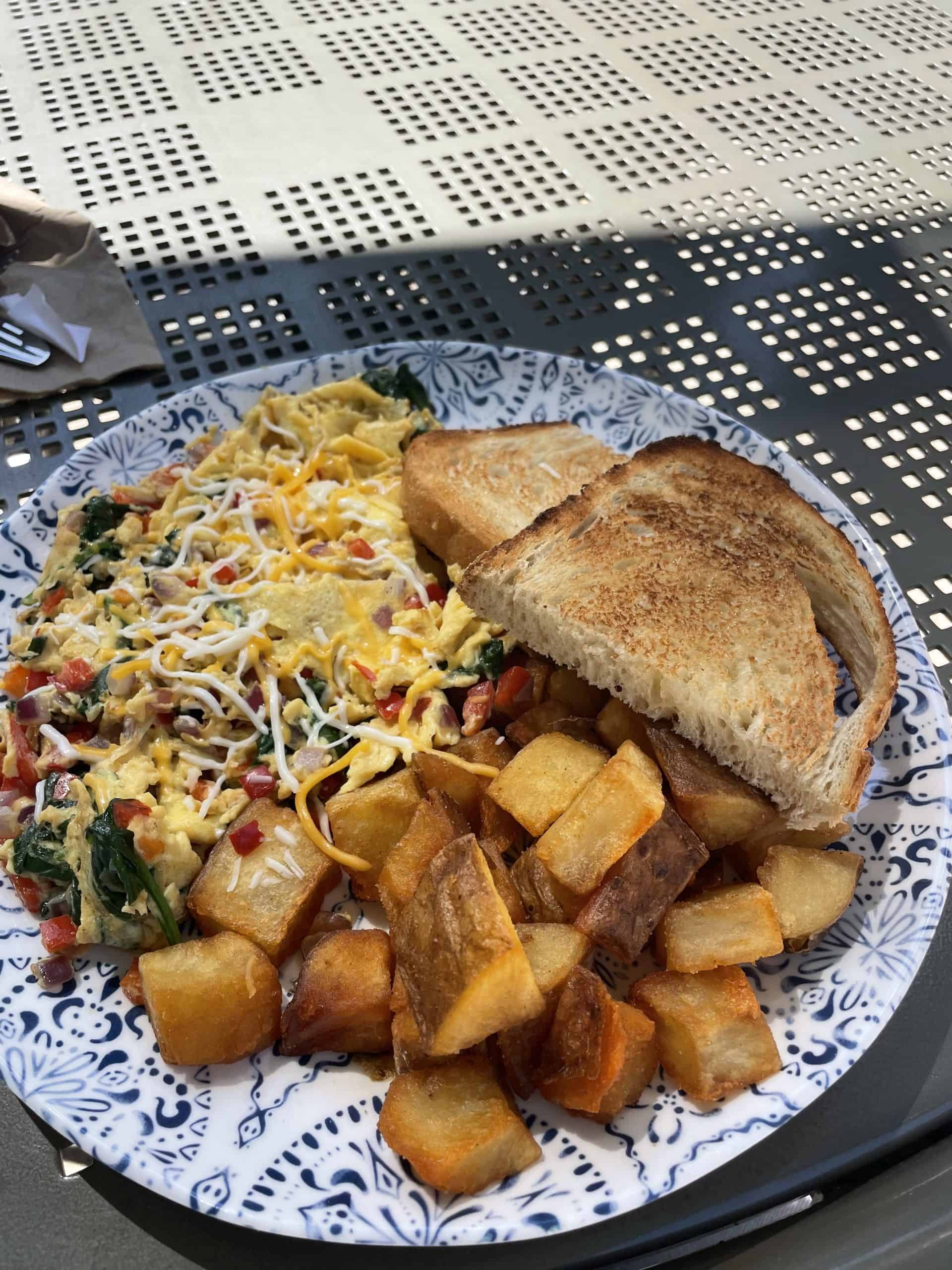 breakfast plate with scrambled eggs, potatoes and sliced toast