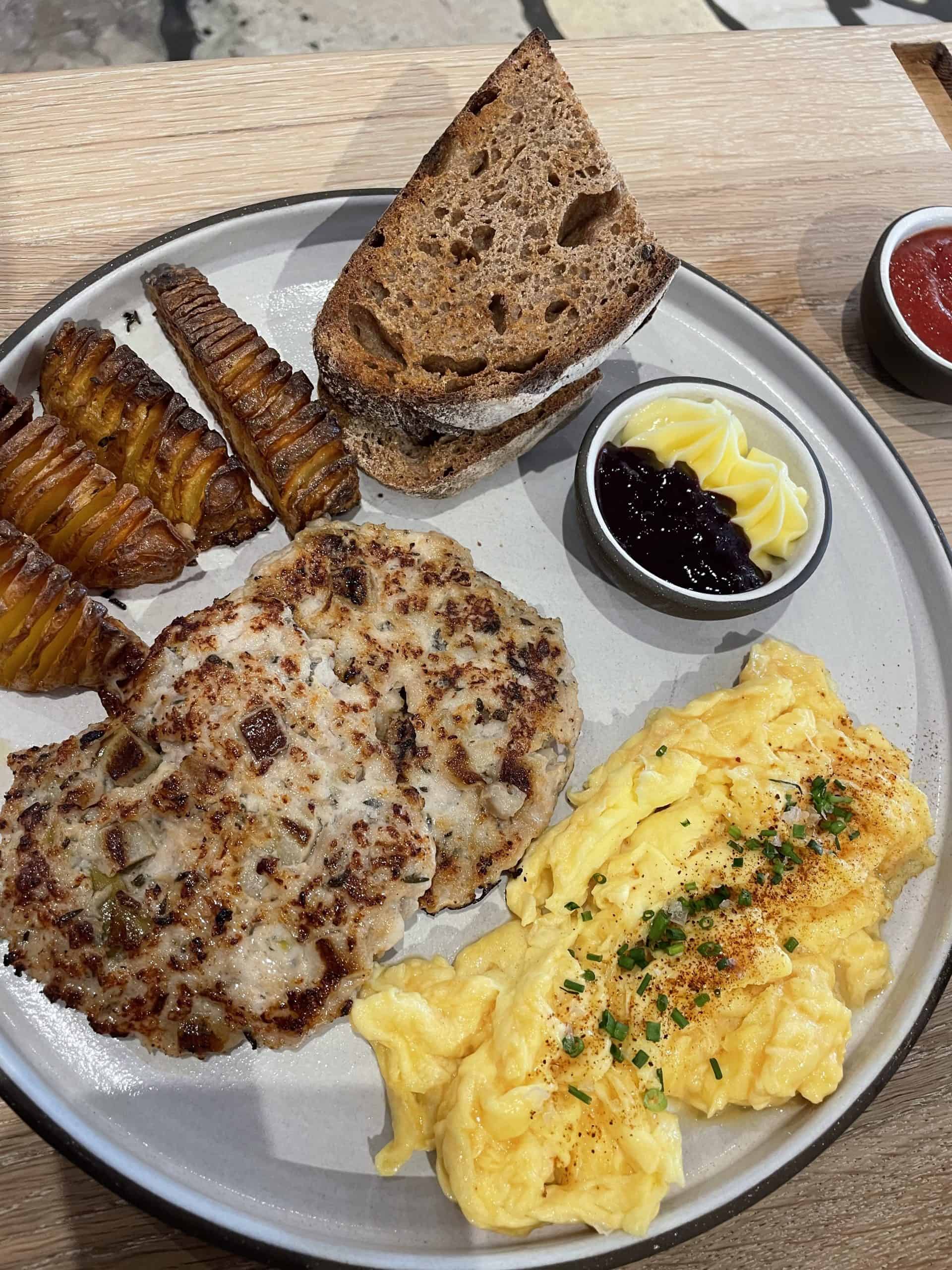breakfast plate from Eller bakery with sourdough, chicken sausage, potatoes and scrambled eggs on a white plate