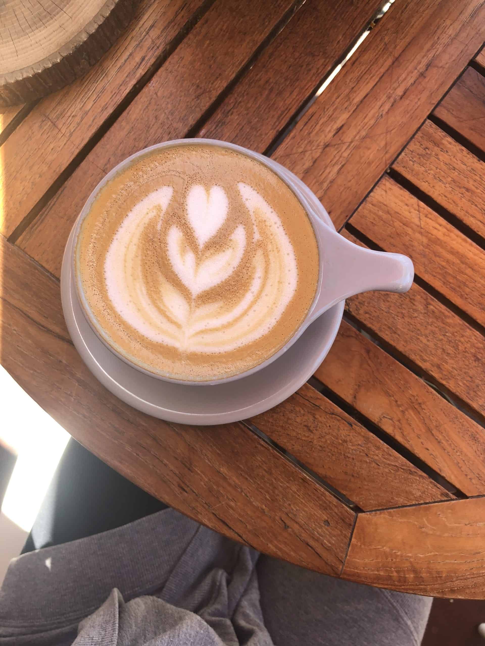 a latte in a grey mug on top of a wooden table
