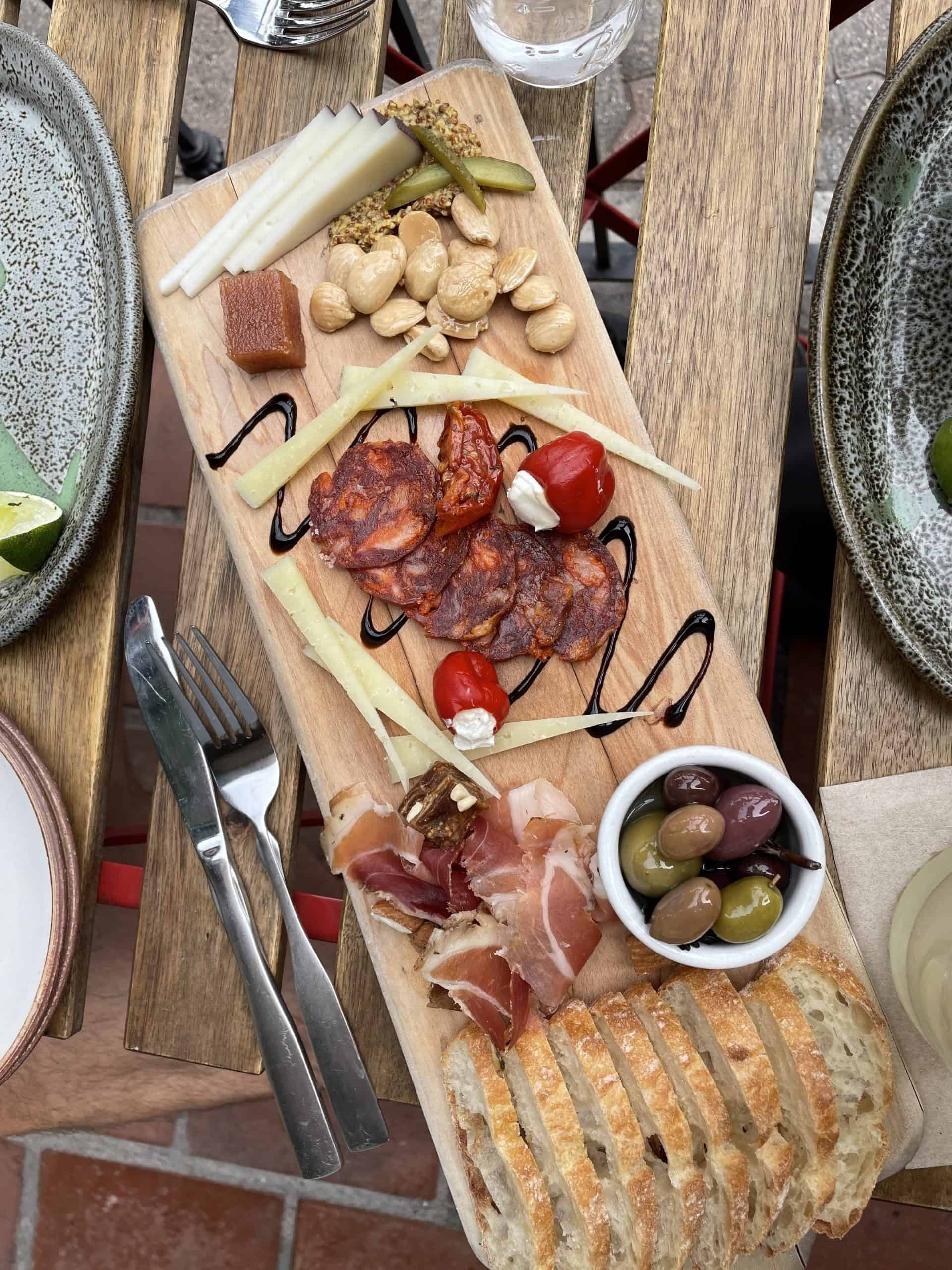 cheese board from The Cellar in San Clemente with cheeses, cured meats, sliced bread and olives