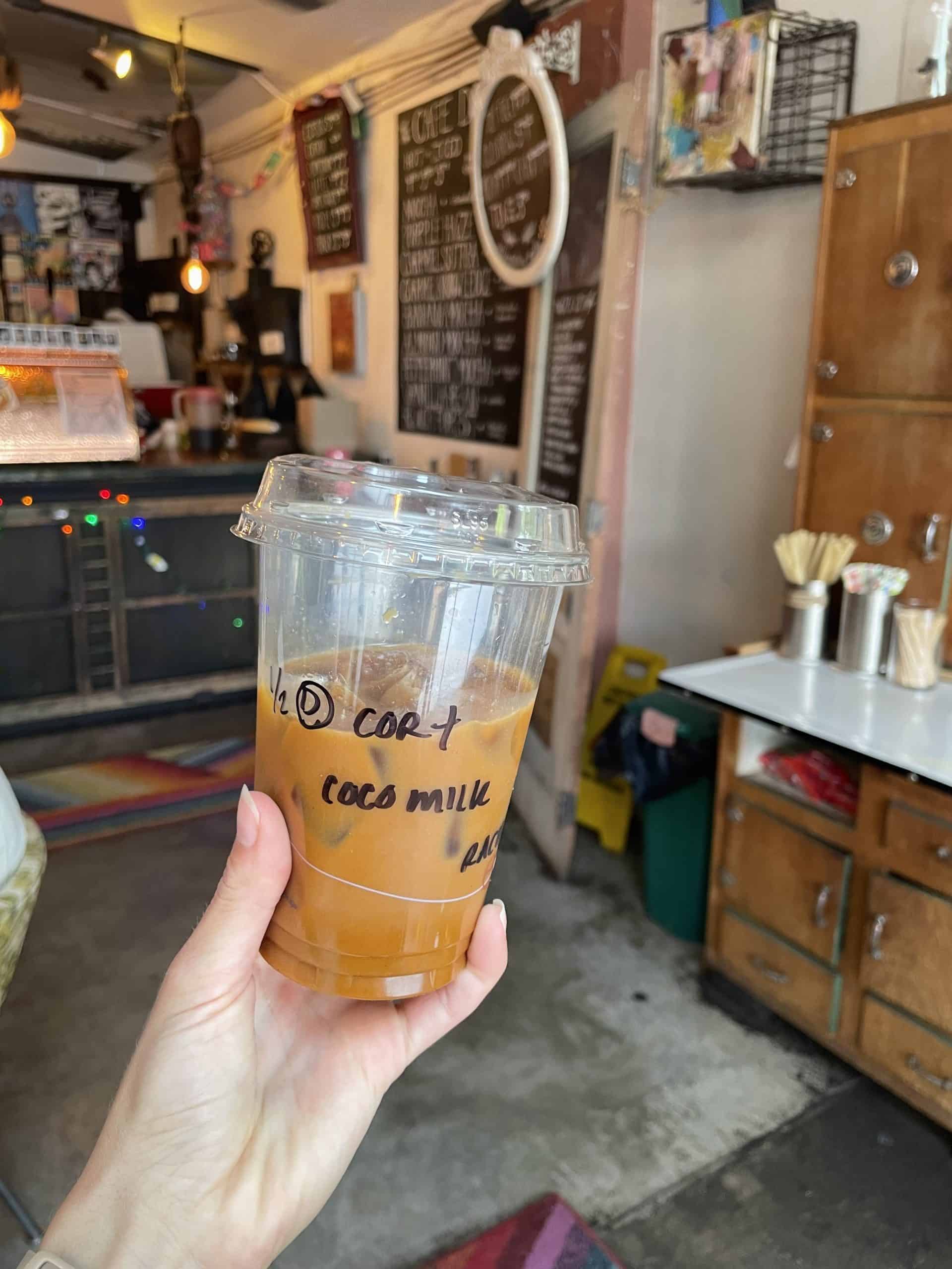 an iced coffee drink with a coffee bar and chalkboard behind it