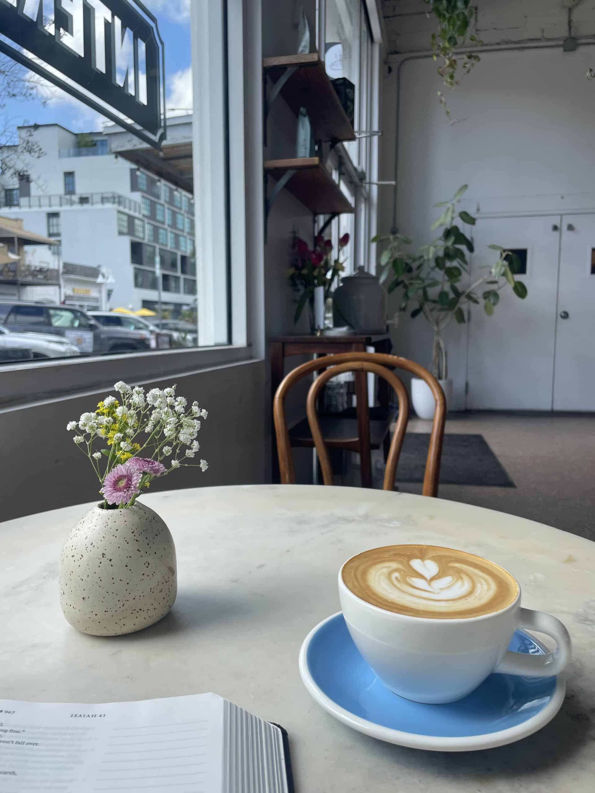a cappuccino in a white ceramic cup with a blue saucer underneath at a coffee shop in St. Pete