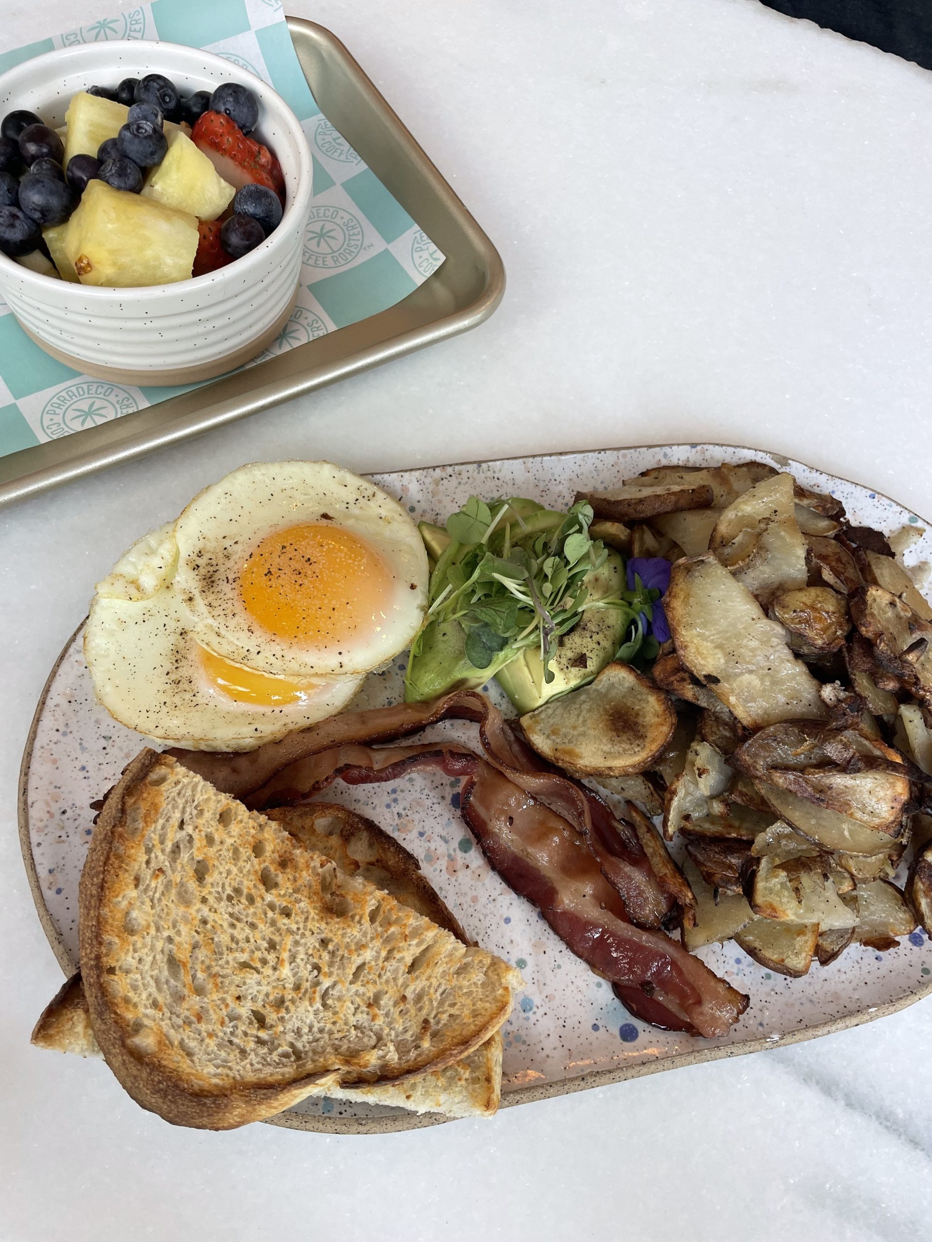 a breakfast plate with sourdough, eggs, potatoes and bacon at Paradeco 