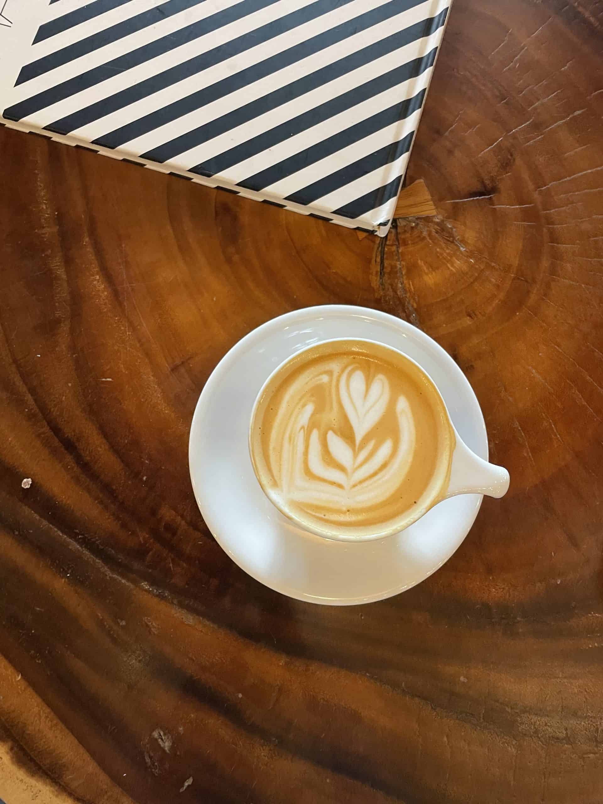 a flat white coffee with a heart latte art on top of a wooden table