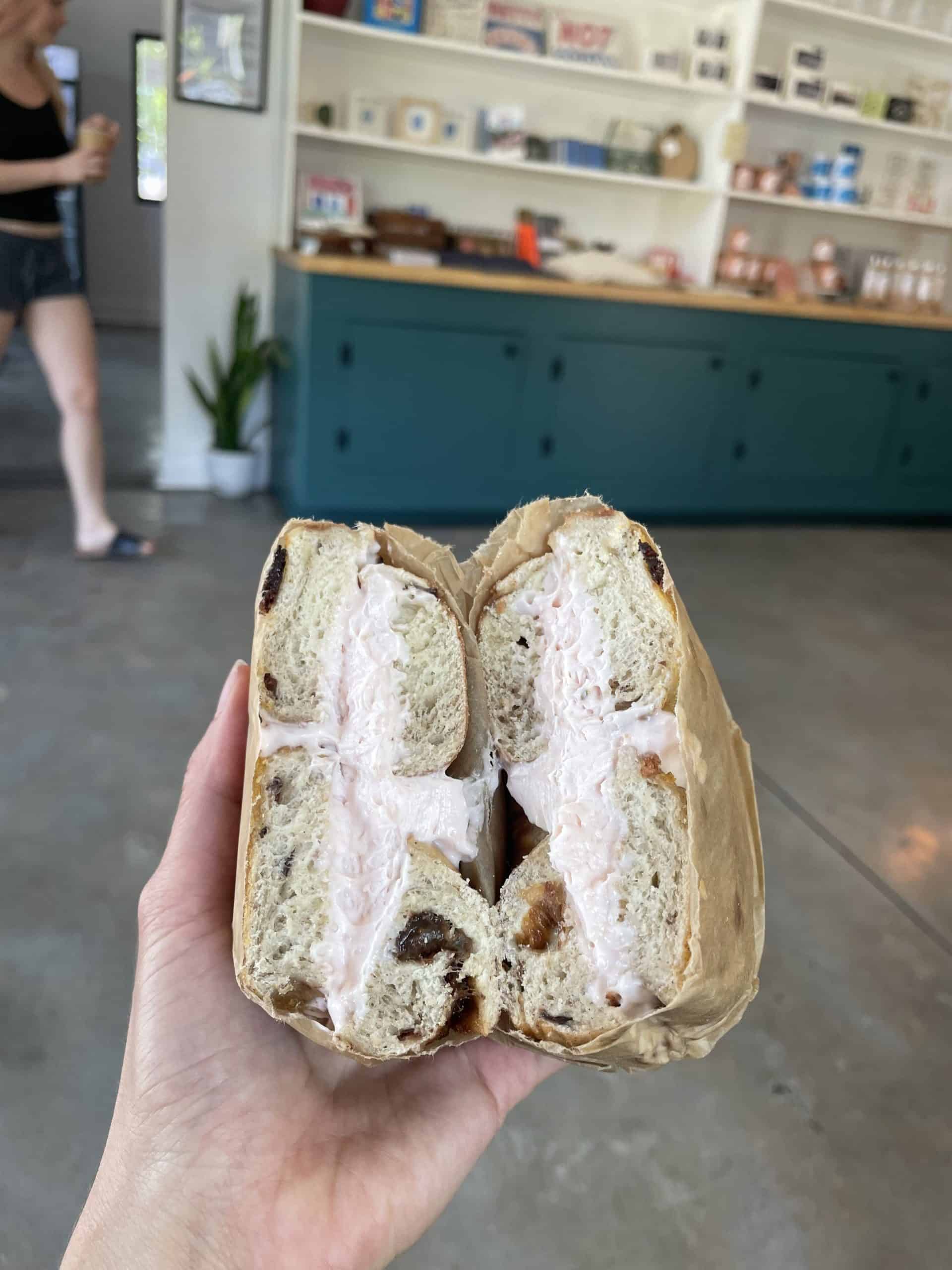 cinnamon raison bagel with strawberry cream cheese being held at Pete's Bagels